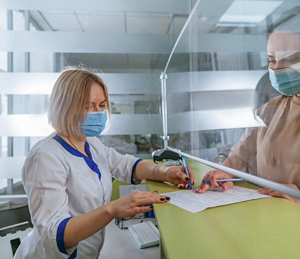 nurse at reception helping a patient